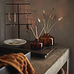 Ett rustikt träfat från Affari of Sweden, dekorerat med bruna glasvaser och en smyckesställning i en varm och mysig inredning.