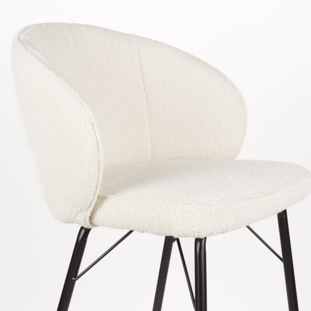 Närbild på Barstol JOA Vit med mjuk, vit klädsel i polyester och svarta metallben – stilren design med hög sittkomfort.