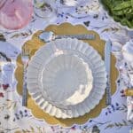 Elegant dukning med Hulda-servisen från Affari of Sweden i elfenbensvitt stengods, uppdukad på en blomstrande bordsduk med detaljer i guld.