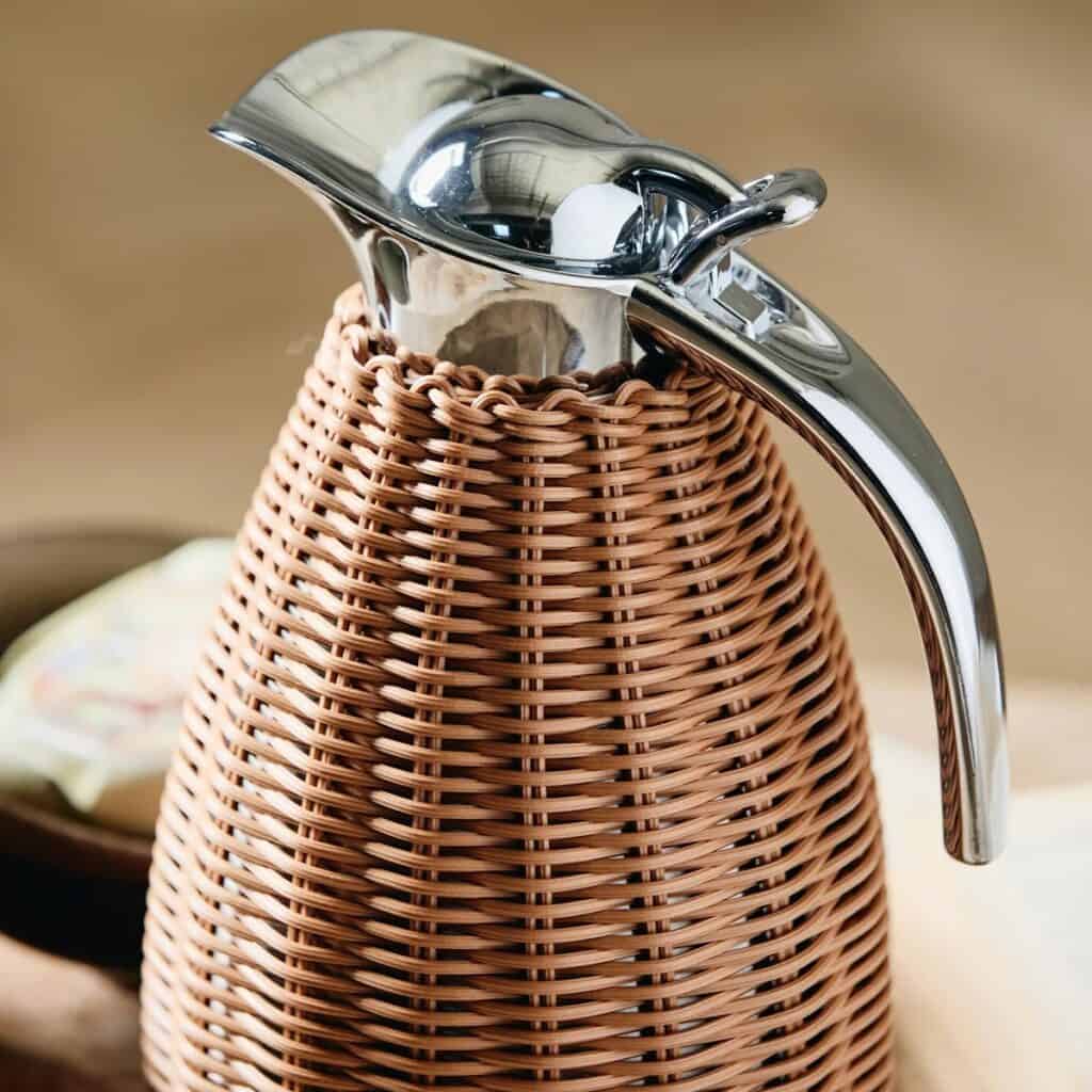 Närbild på termoskannan från Nordal med handvävd rotting och en elegant kromad topp.