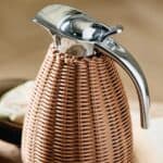 Närbild på termoskannan från Nordal med handvävd rotting och en elegant kromad topp.