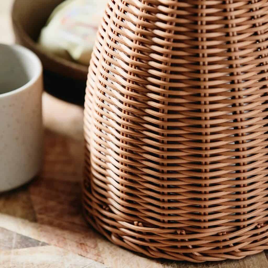 Närbild på den handvävda rottingstrukturen hos Nordals termoskanna, placerad på ett träbord.