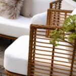 Närbild av Covelo utemöbel fåtölj från Brafab i naturfärgad konstrotting med vita dynor, som skapar en stilren och inbjudande uteplats.