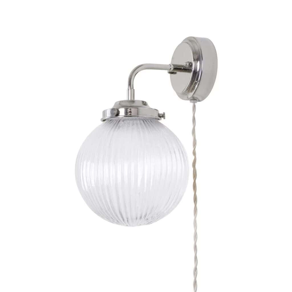 Vägglampa Eivor från Strömshaga med förnicklat fäste och räfflad, rund glaskupa, samt en tvinnad sladd för en klassisk och stilren look.