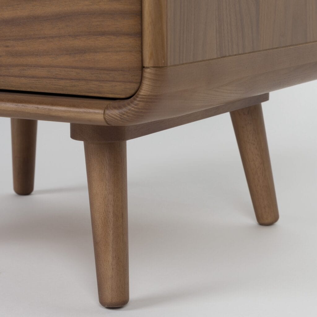 Närbild av byrå RISE i valnöt som visar de rundade hörnen och de smala, lätt utställda benen i trä.