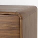 Närbild av byrå RISE i valnöt som visar de mjukt rundade hörnen och den eleganta trästrukturen.