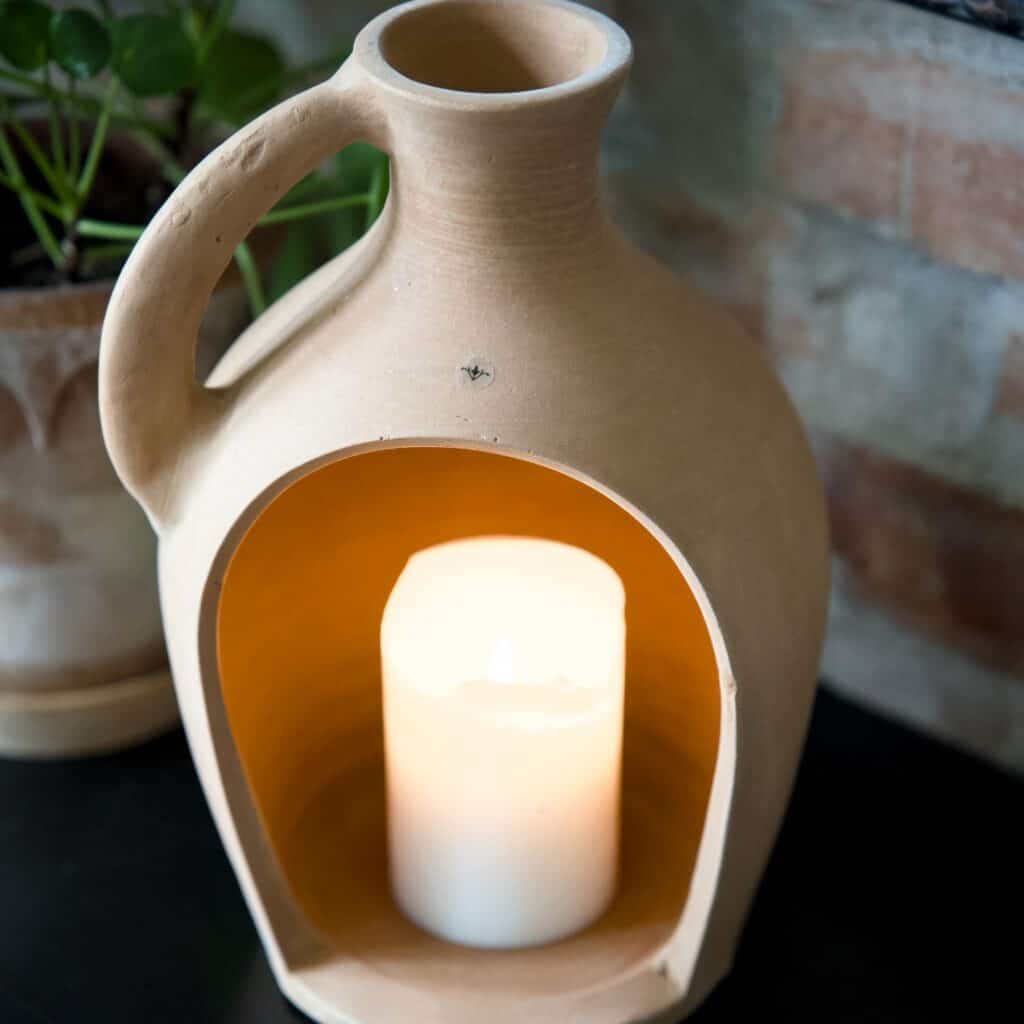 Floda Lykta i terrakotta från Affari of Sweden med ett tänt blockljus inuti, fotograferad från ovan för att visa dess rustika design och varma sken.