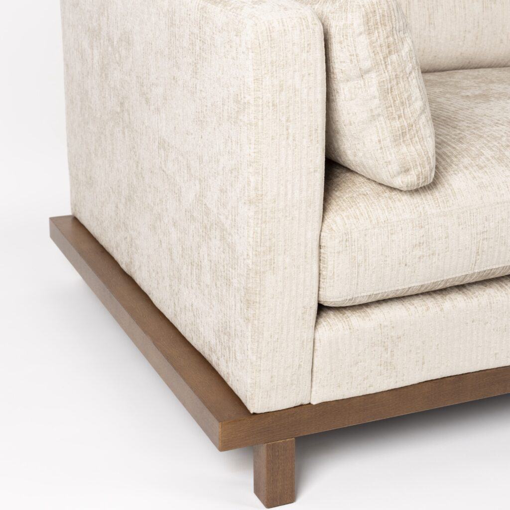 Detalj av Zuiver Blossom 3-sits soffa i sandfärgat tyg – träsockel i valnöt och strukturvävt tyg