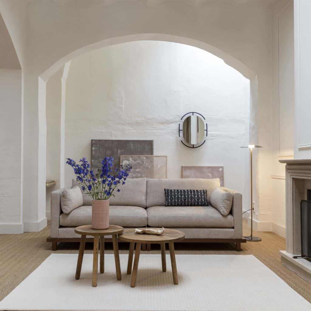 Zuiver Blossom 3-sits soffa i sandfärgat tyg med valnötsram – Japandi-stil i ljust rum med spegel och konst.