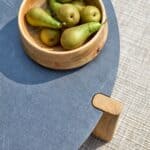 Närbild av Brafab Domino soffbord med antracit laminatskiva och teakben, dekorerat med en träskål fylld med gröna päron.