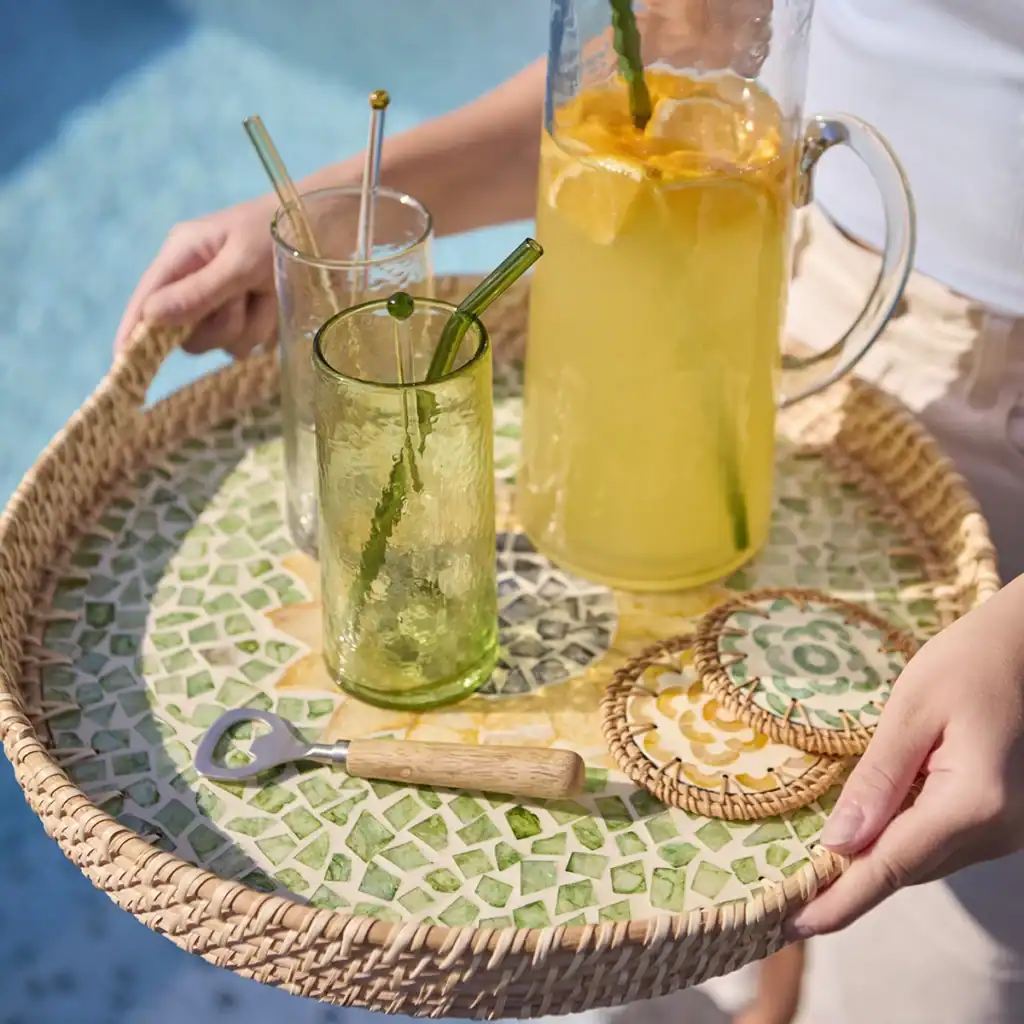 Två glas och en karaff på en bricka med SUNNY glasunderlägg