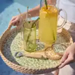 Två glas och en karaff på en bricka med SUNNY glasunderlägg