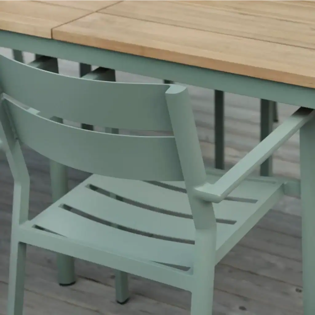 DELIA karmstol inplacerad vid ett bord i trä, visad från sidan.