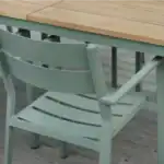 DELIA karmstol inplacerad vid ett bord i trä, visad från sidan.