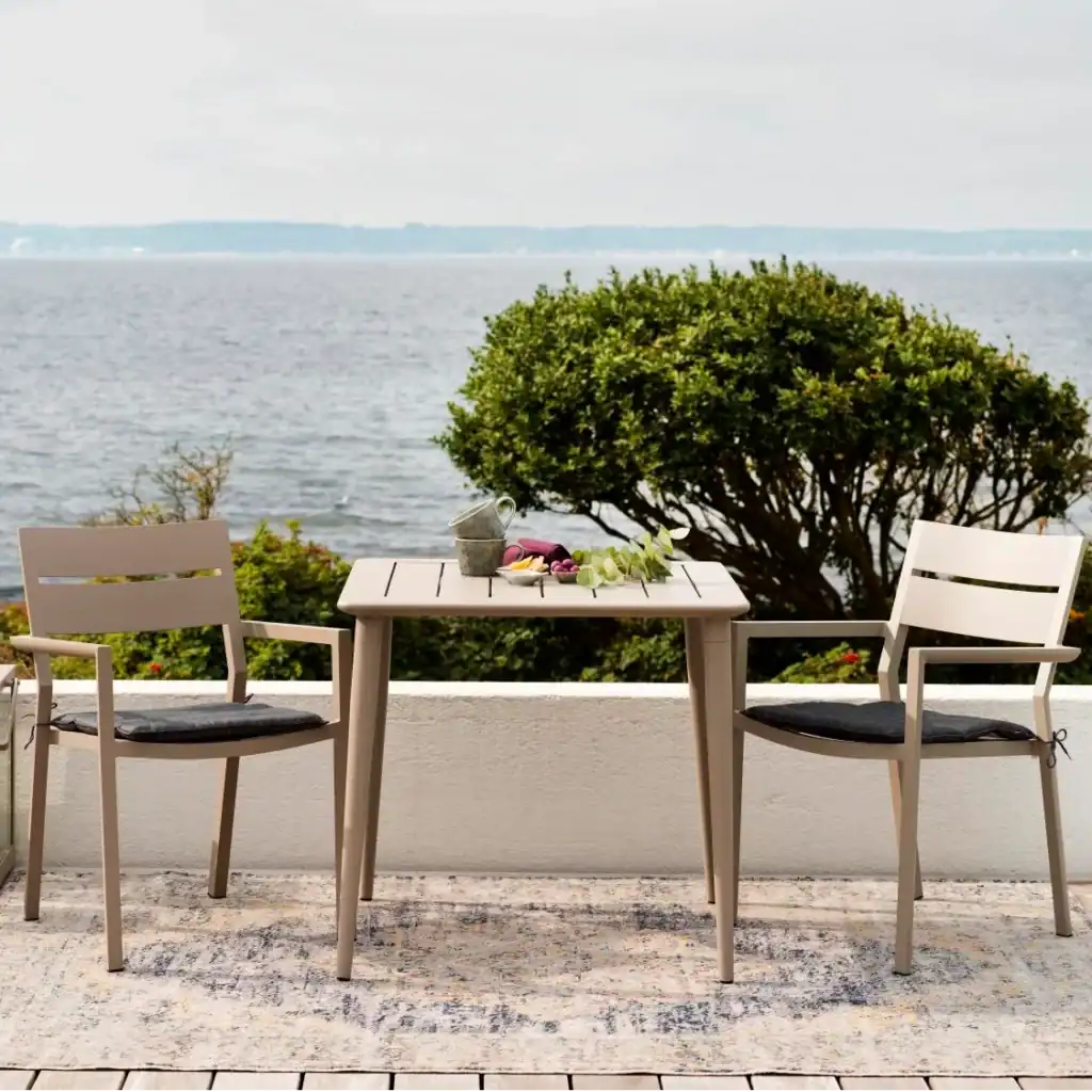 Flera DELIA karmstolar i khaki uppställda runt ett matbord på en modern uteplats.