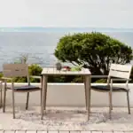 Flera DELIA karmstolar i khaki uppställda runt ett matbord på en modern uteplats.