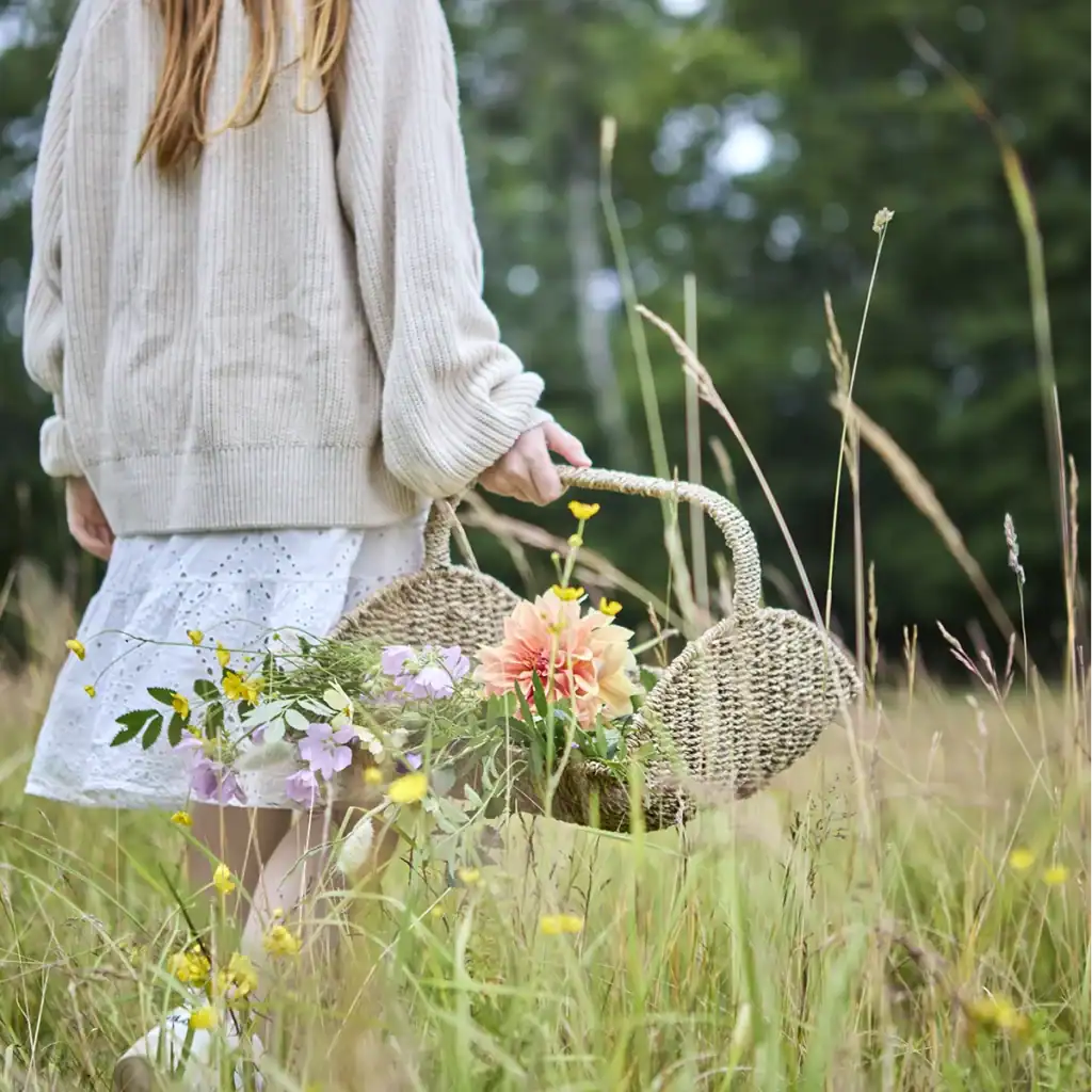 Korg COLLECT från Affari of Sweden bärs i blomsteräng av kvinna i vit klänning.