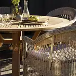 CIRCUS matbord natur teak från Brafab dukat för middag med glas, karaffer och korgstolar i kvällssol.