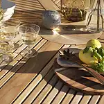 Närbild på CIRCUS matbord natur teak med citroner, träbestick och glas på den ribbade bordsskivan.