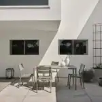 DELIA matstolar i dusty green i solbelyst uteplats med modern fasad.