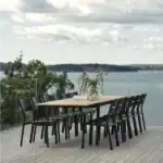 Flera DELIA matstolar i svart runt ett matbord på en altan