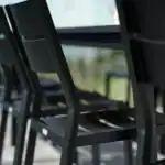 DELIA matstolar i svart under ett bord, sedd från sidan