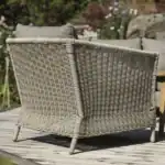 Baksida på fåtölj beige Brafab Aster i närbild med trädgård i bakgrunden