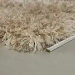 Detaljbild på mattan HAIRY i beige från Zuiver, med en linjal bredvid som visar dess höjd och fluffiga struktur.