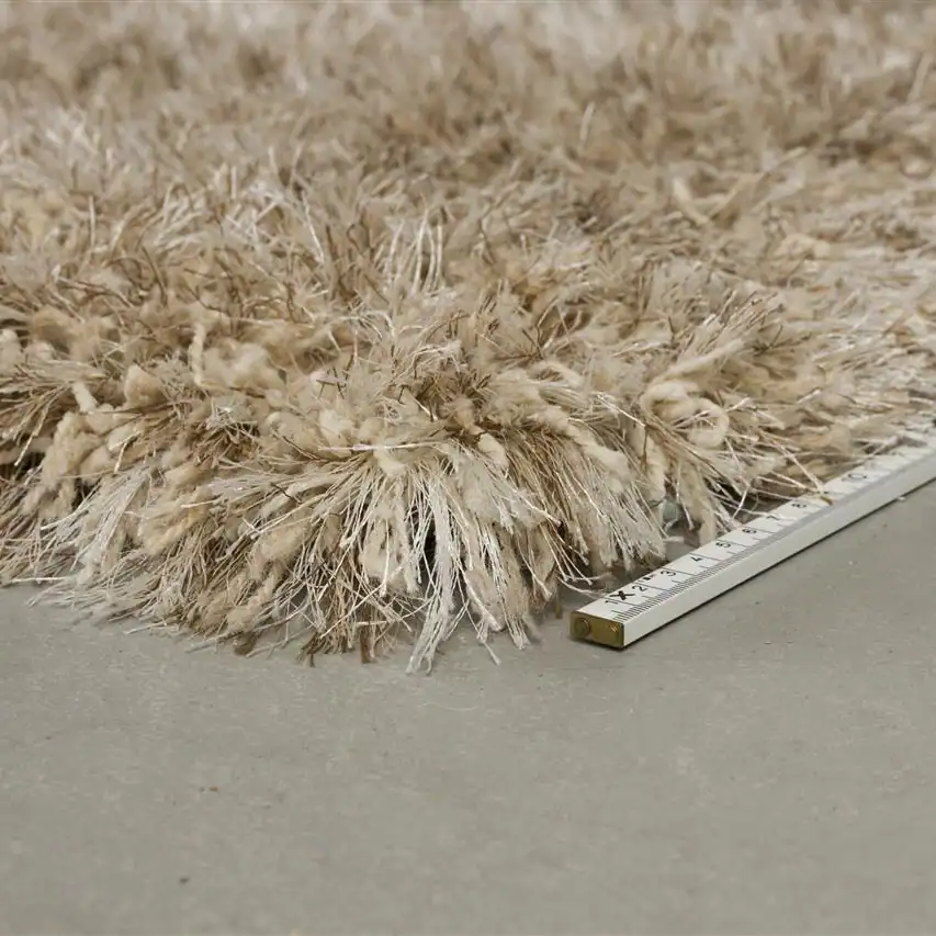 Detaljbild på mattan HAIRY i beige från Zuiver, med en linjal bredvid som visar dess höjd och fluffiga struktur.