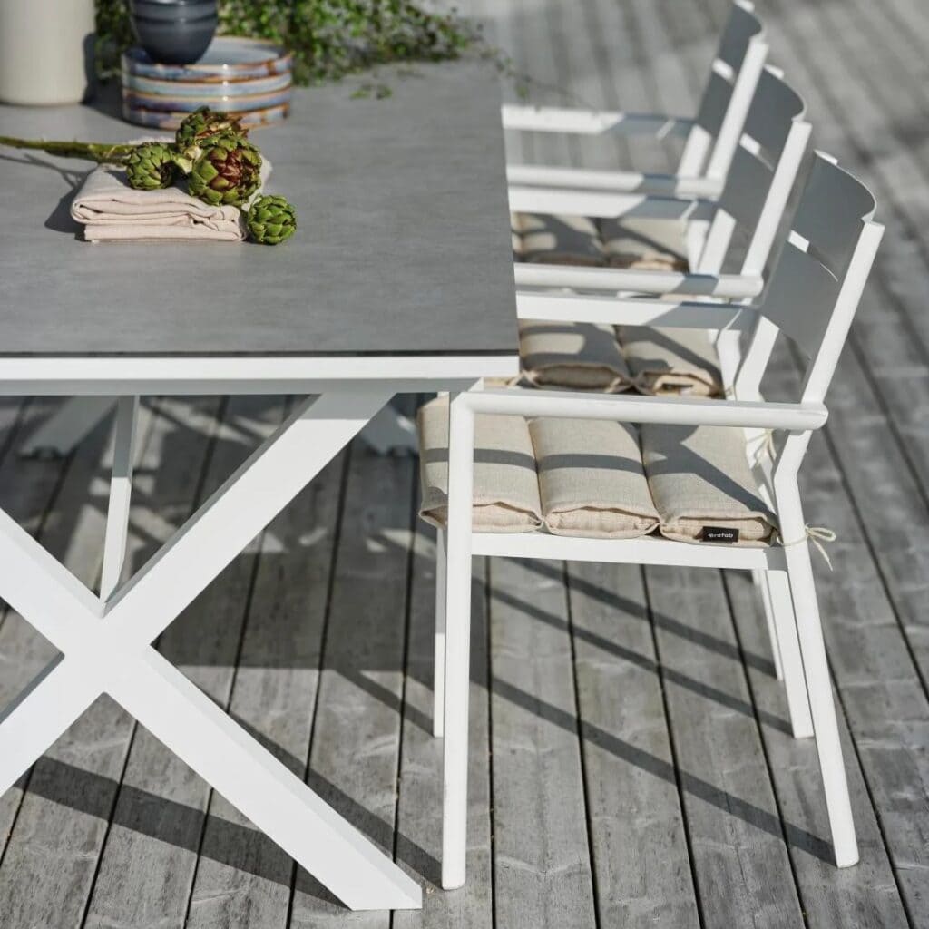 Flera vita Delia karmstolar från Brafab i aluminium uppställda vid ett modernt utomhusbord med grå bordsskiva.