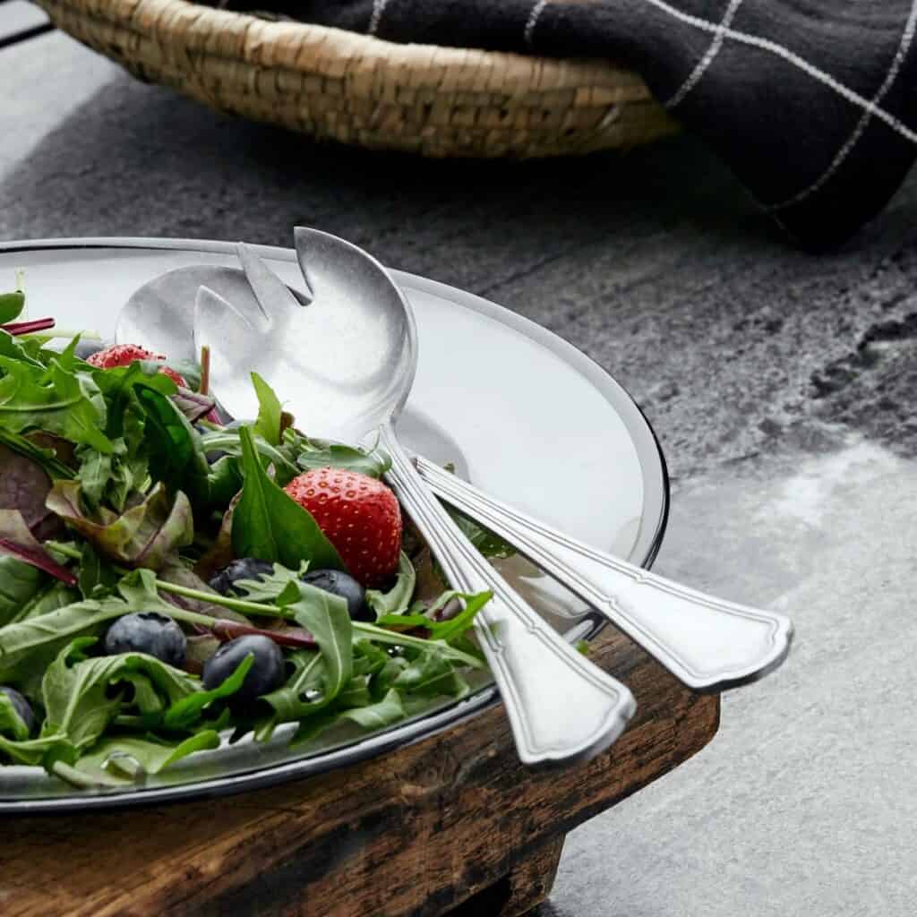 CARUM salladsbestick i vintage stil från Nordal på ett serveringsfat med färsk sallad och bär