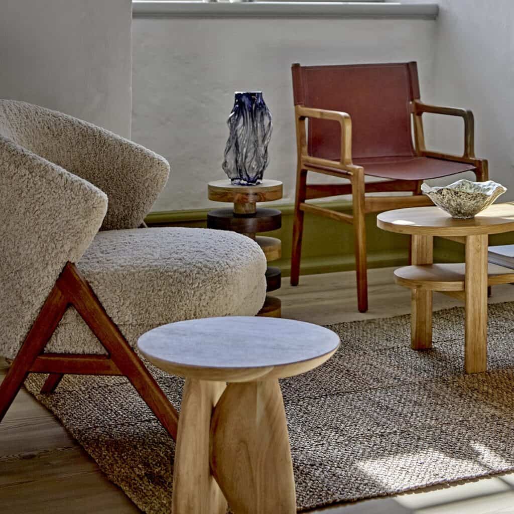 Camino fåtölj i beige teddyklädsel med mörka träben i rubberwood från Bloomingville, placerad i ett stilrent vardagsrum med naturliga träbord och dekorativa detaljer.