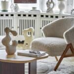 Camino fåtölj i beige teddyklädsel med ben i mörk rubberwood från Bloomingville, placerad i ett ljust vardagsrum med skulpturala dekorationer.