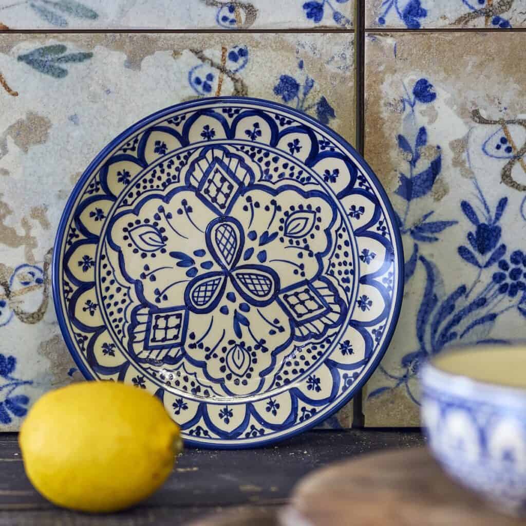 Handmålad tallrik KARLIE blå 19 cm från Bloomingville i stengods, dekorativ assiett med blått mönster mot kakelbakgrund och citron i förgrunden.