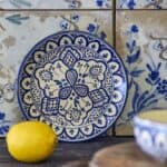Handmålad tallrik KARLIE blå 19 cm från Bloomingville i stengods, dekorativ assiett med blått mönster mot kakelbakgrund och citron i förgrunden.