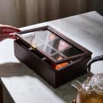 Puyo förvaringslåda med glaslock i mangoträ från Nordal – öppen låda med sex fack fyllda med tepåsar.