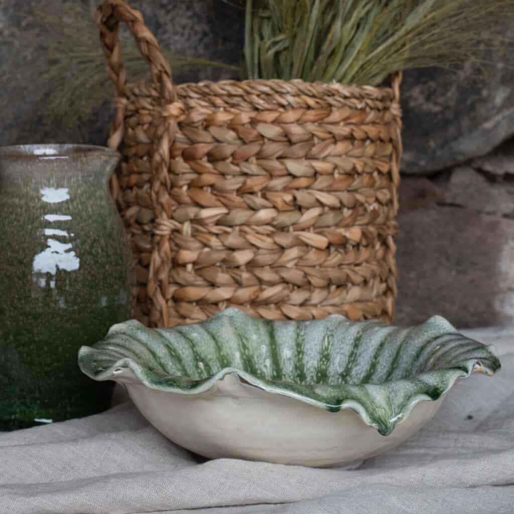 Skål IVY grön terrakotta dekorativ med vågig kant från Wikholm Form i miljö med flätad korg och grön vas