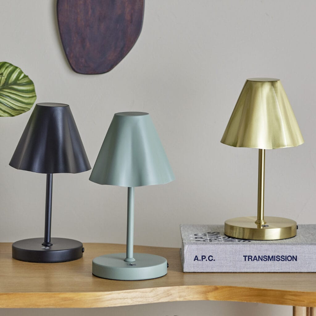 Tre laddningsbara bordslampor från Bloomingville – Lianna i svart, grön och mässing på ett träbord.