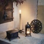 Ljusstake i gjutjärn i julmiljö – liten julgransfot med tända ljus, gran och julstämning.