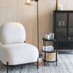 Svart sidobord i metall och rotting bredvid fåtölj i ljust tyg – Makoto från Hemlängtan i vardagsrumsmiljö.