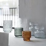 DOTTI ljuslyktor i olika färger placerade på en vit hylla vid fönster.