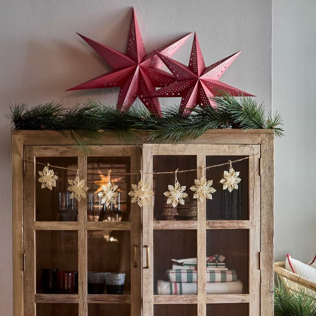 Röda julstjärnor UNI på skåp med granris och juldekoration – Hemlängtan.