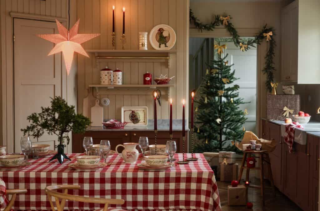Lantlig juldukning med rödvitrutig duk, mässingsljusstakar, julgran och porslin i klassisk stil från Strömshaga.