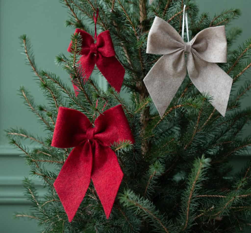 Liten röd rosett i gran – juldekoration i textil från Hemlängtan.