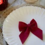 Röd rosett 10×13 cm placerad på tallrik i en enkel juldukning.