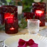 Tända röda och klara glaslyktor från Valdir-serien på juldukad bord.