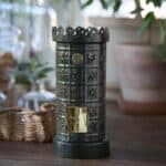 Grön värmeljuslykta i kakelugnsstil fotograferad i en mysig miljö.