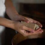 Händer som löddrar en Aleppotvål över en kopparfärgad skål med vatten