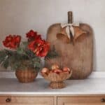 Fruktskål i naturfärgad rotting på fot fylld med äpplen på köksbänk i varm miljö