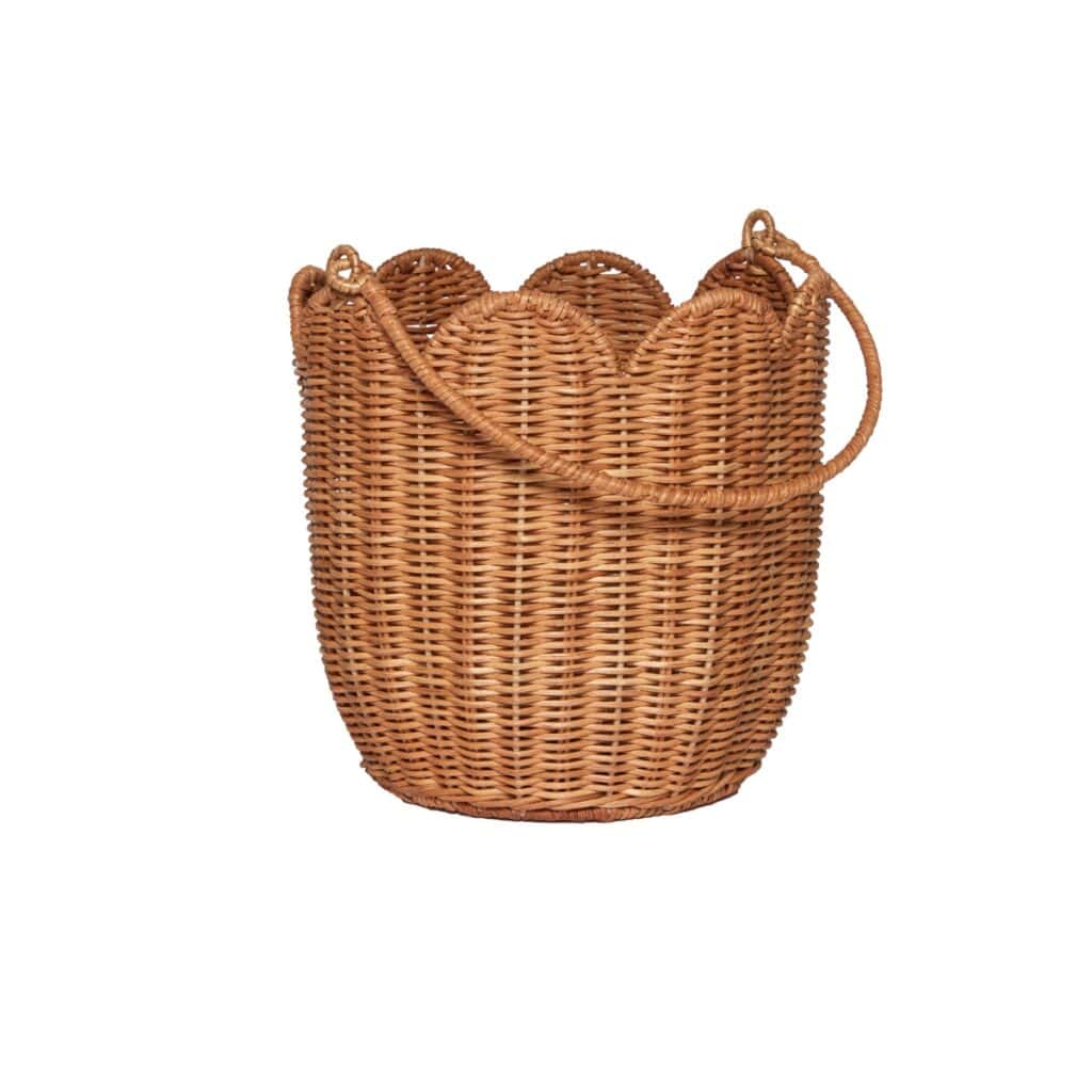 Handgjord korg i naturfärgad rotting med vågig kant och handtag på vit bakgrund.